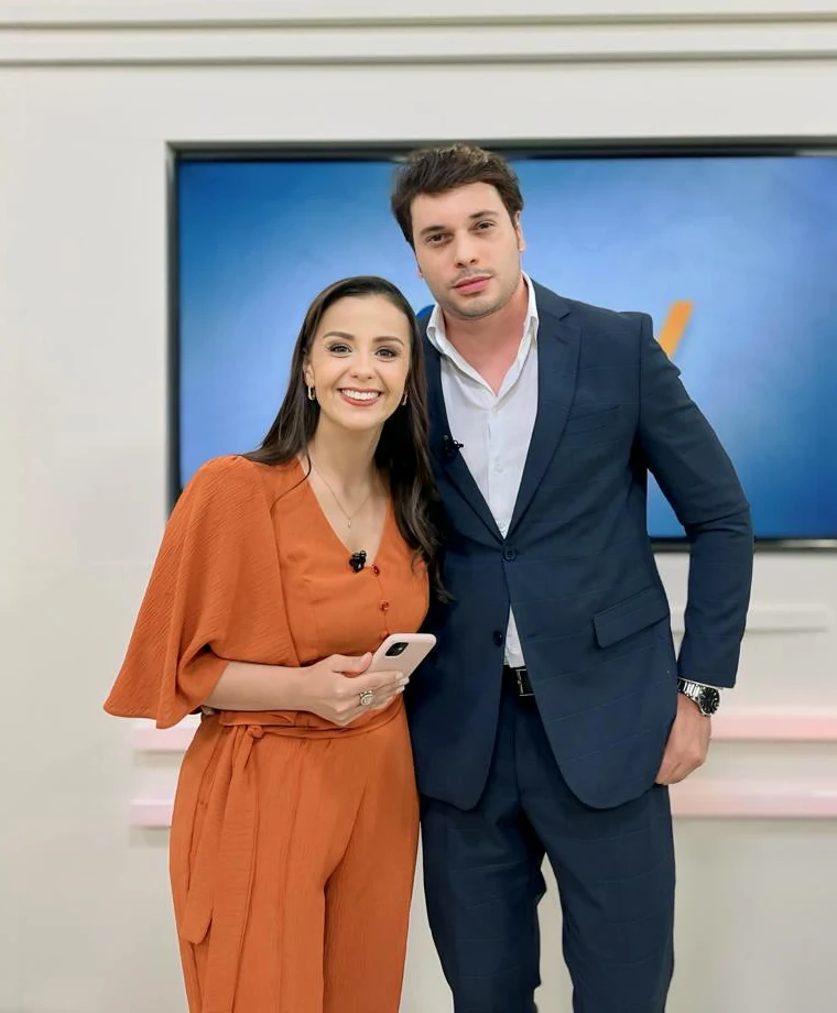 Dr. Rossini Monteiro de terno com a apresentadora de laranja no estúdio do MGTV.